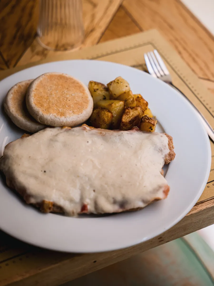 Cotoletta alla bolognese con prosciutto crudo e Grana servita da Le Moline con patate al forno e tigelle